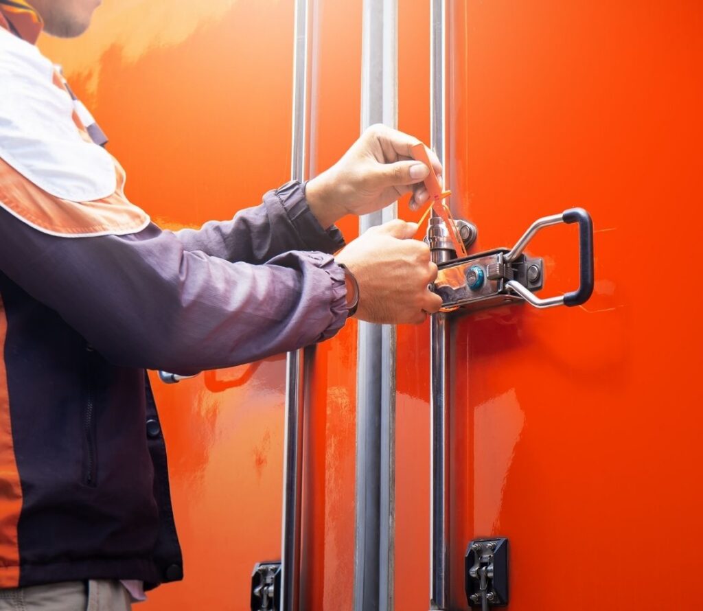 Worker locking a shipping container to ensure secure transloading and bonded warehousing services in Tampa, FL.