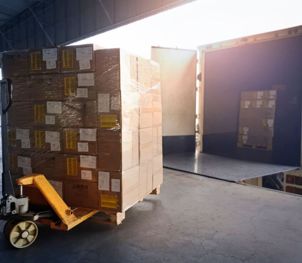 Workers restacking pallets and securing freight in New Braunfels warehouse for shipment compliance.